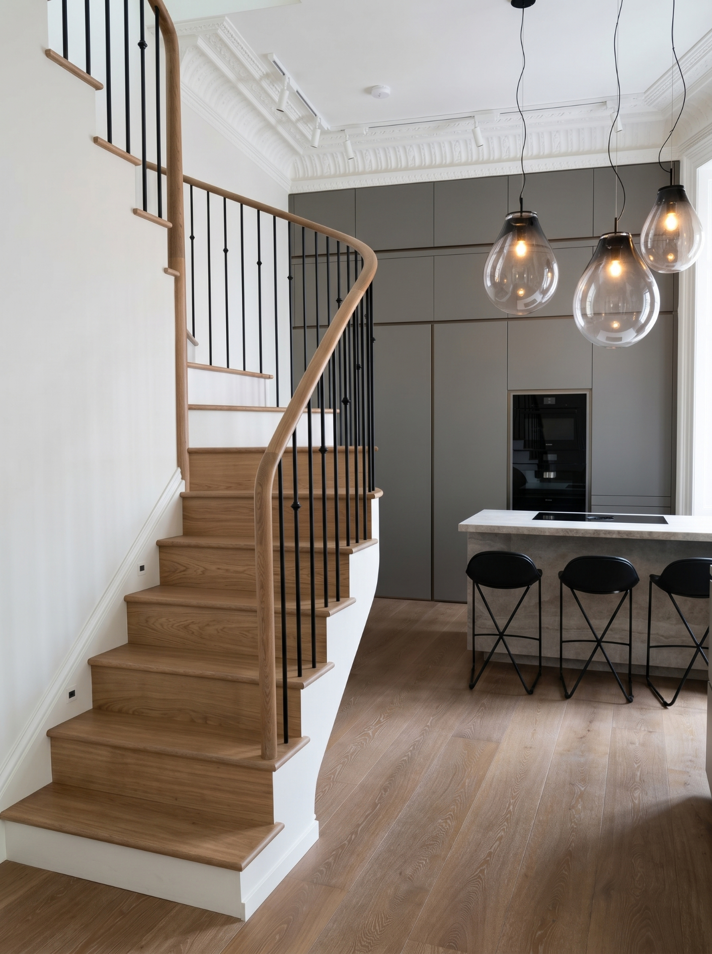 Curved oak staircase beside a bespoke kitchen